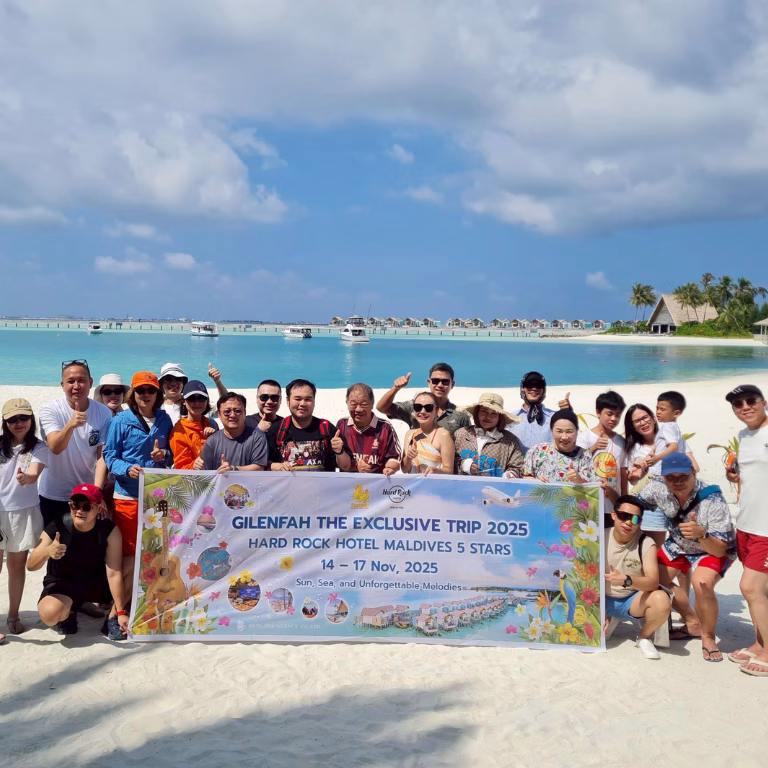 ภาพถ่ายหมู่คณะผู้บริหารและพนักงานทริป Gilenfah The Exclusive Trip 2025 บนหาดทรายขาว พร้อมป้ายแบนเนอร์และฉากหลังเป็นทะเลมัลดีฟส์สีฟ้าคราม