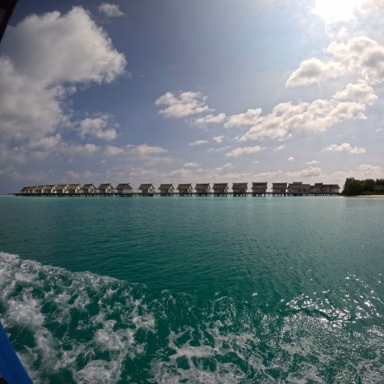 ทัศนียภาพแนวยาวของวิลลากลางน้ำ (Overwater Villas) โรงแรม Hard Rock Hotel Maldives กลางทะเลสีมรกต ถ่ายจากมุมมองบนเรือสปีดโบ๊ท